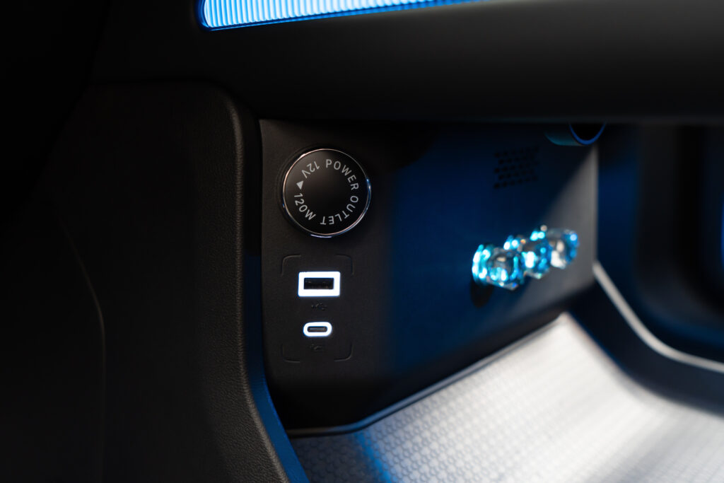 Tomada e entradas USB do Jetour G700, na cabine com iluminação ambiente em azul